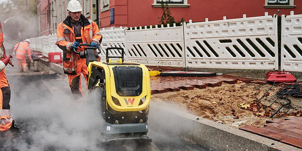 stavebný robotník pracujúci s vibračnou doskou na stavenisku v centre mesta