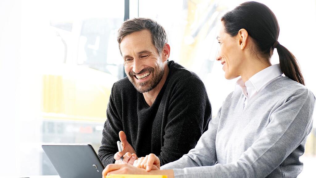 Predajkyňa Wacker Neuson radí zákazníkovi ohľadne jazdených stavebných strojov a zariadení sediac pred notebookom.