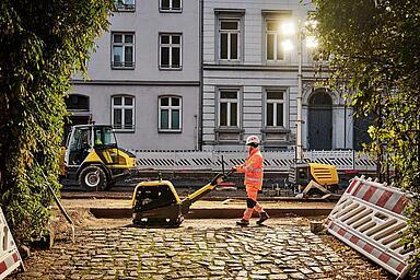 Man working with dumper on road with old expensive houses in the background