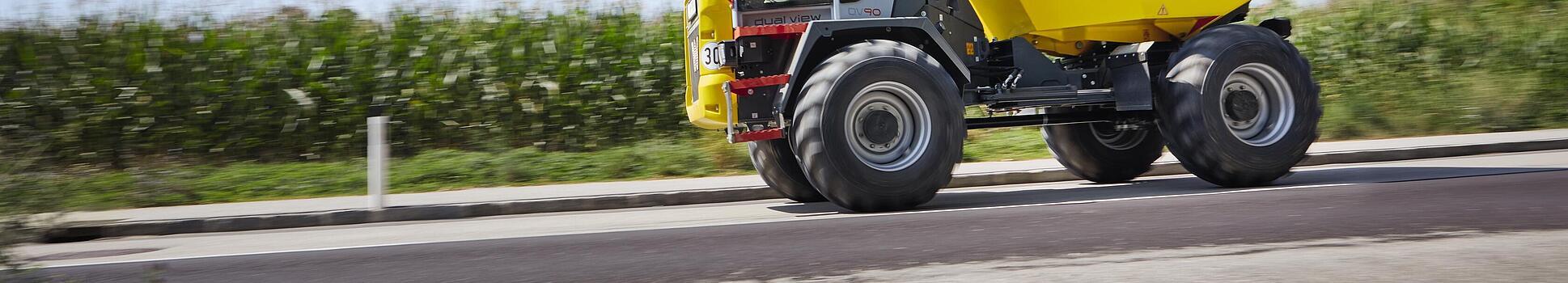 Dvojitý pohľad Dumper DV90 jazdí po ceste.