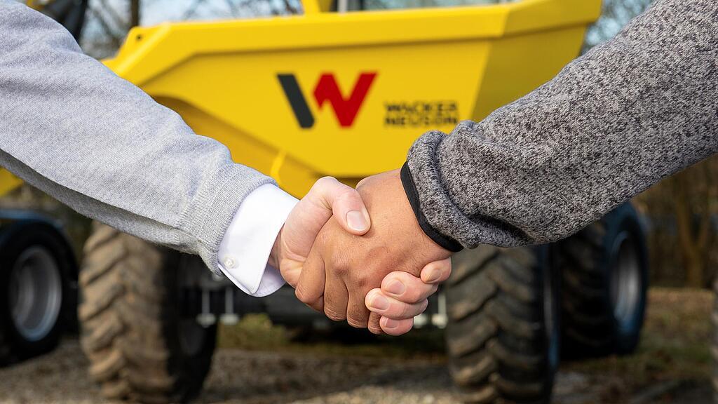 Handshake between Wacker Neuson advisor and customer in front of Wacker Neuson dumper.