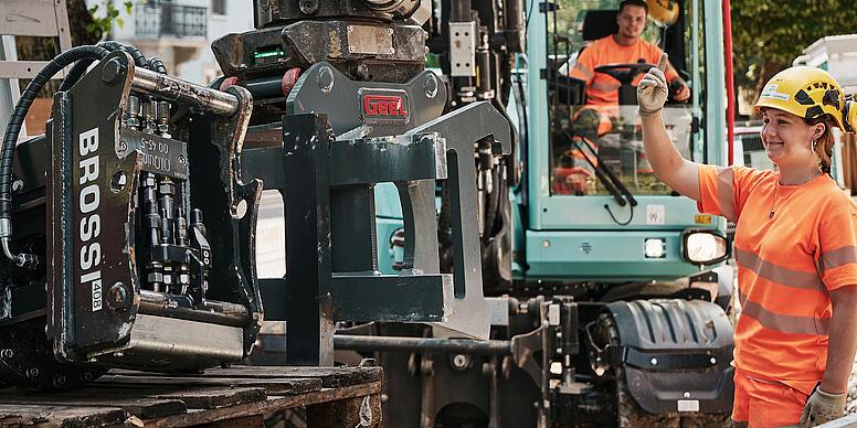 Operátor pripravuje hydraulické príslušenstvo na kolesovom rýpadle Wacker Neuson EW100 na stavebnom dvore v meste.