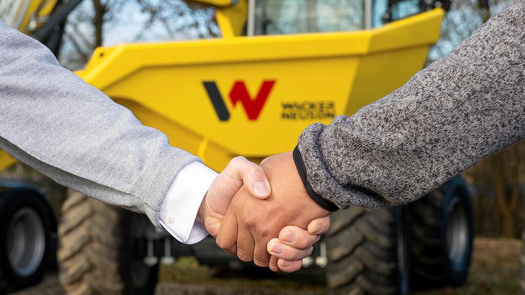 Podanie ruky medzi poradkyňou Wacker Neuson a zákazníkom pred dumprom Wacker Neuson.