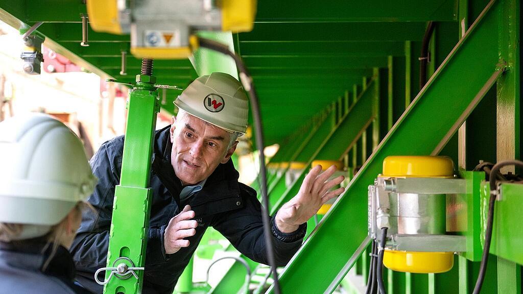 Zamestnanec Wacker Neuson stojí pred príložným vibrátorom a vysvetľuje, ako funguje.