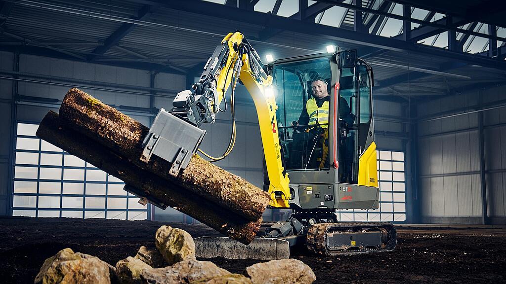 Wacker Neuson Minibagger ET18 mit Greifer beim Verladen von Baumstämmen