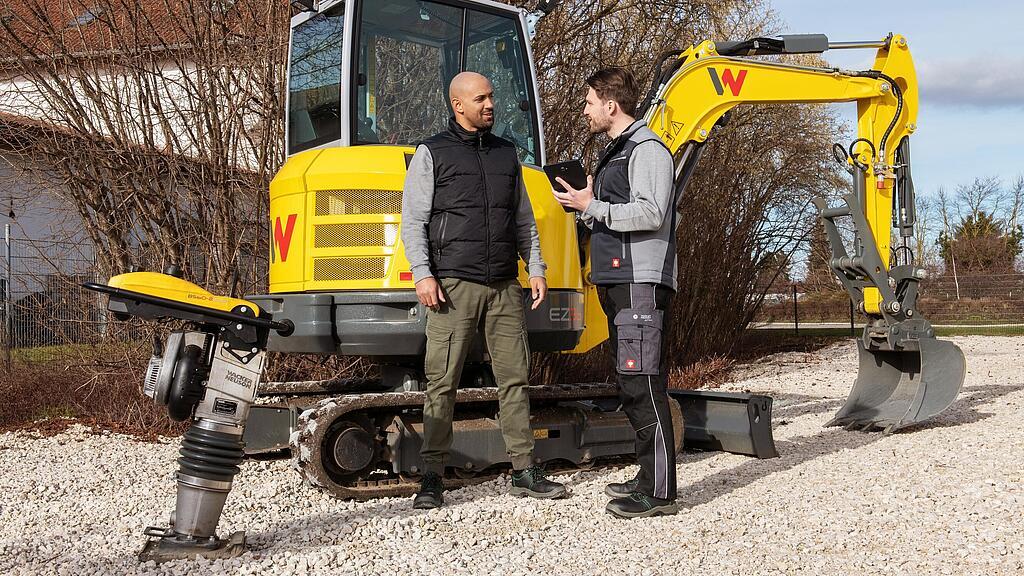 Zamestnanec spoločnosti Wacker Neuson radí zákazníkovi o balíku WeCare pred strojmi Wacker Neuson.