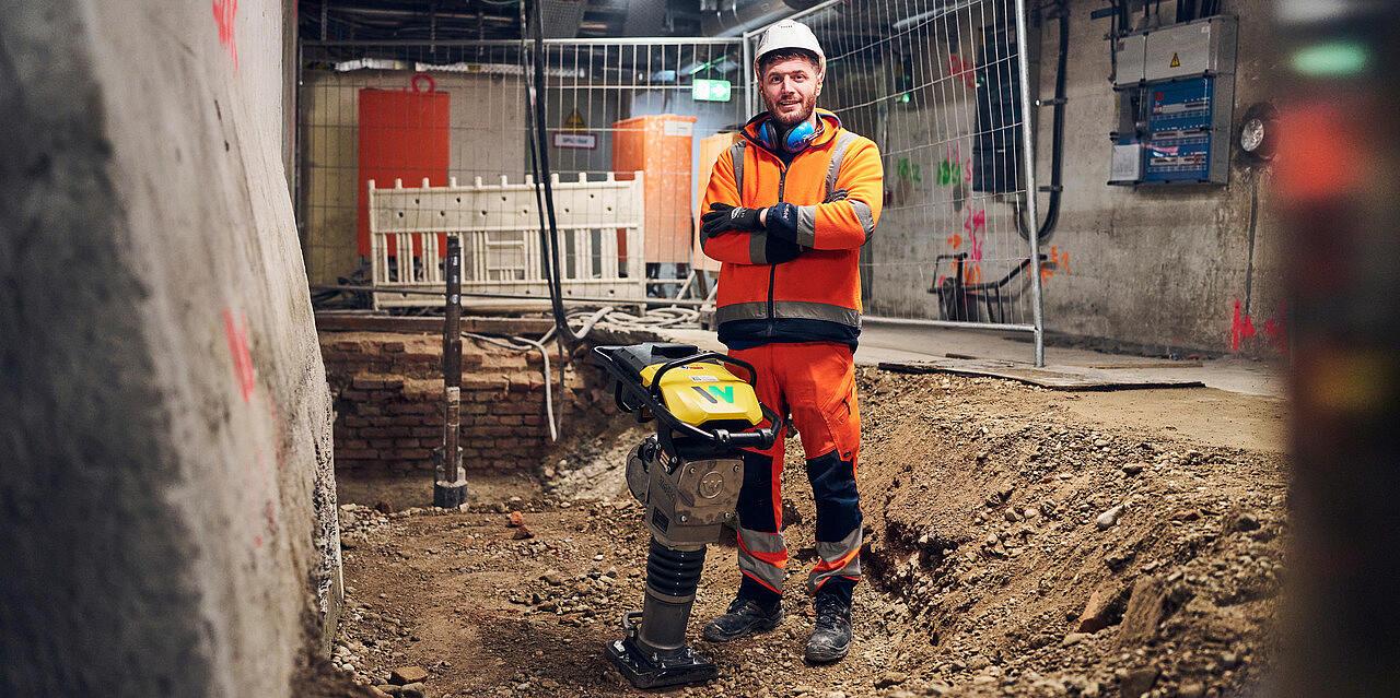 man standing next to battery powered rammer from wacker neuson at construction site