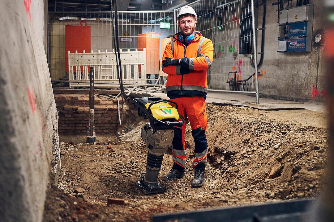 man standing next to battery powered rammer from wacker neuson at construction site